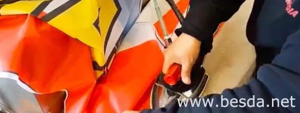 Worker pressing the hem of a printed flag flat after dye-sublimation in a flag workshop